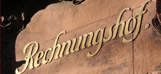 Wandschriftzug Rechnungshof in Gold auf rotbraunen Sandstein